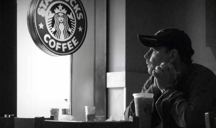 A man looks out the window at a Starbucks cafe.