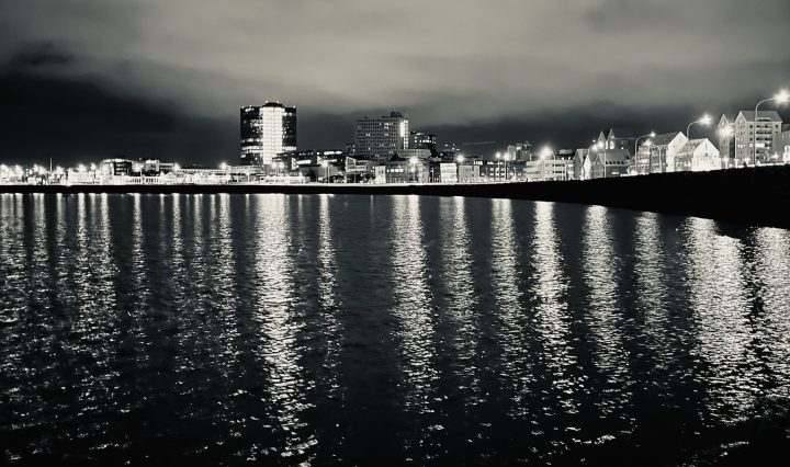 A black and white shot of Reykjavik's coastline at night.