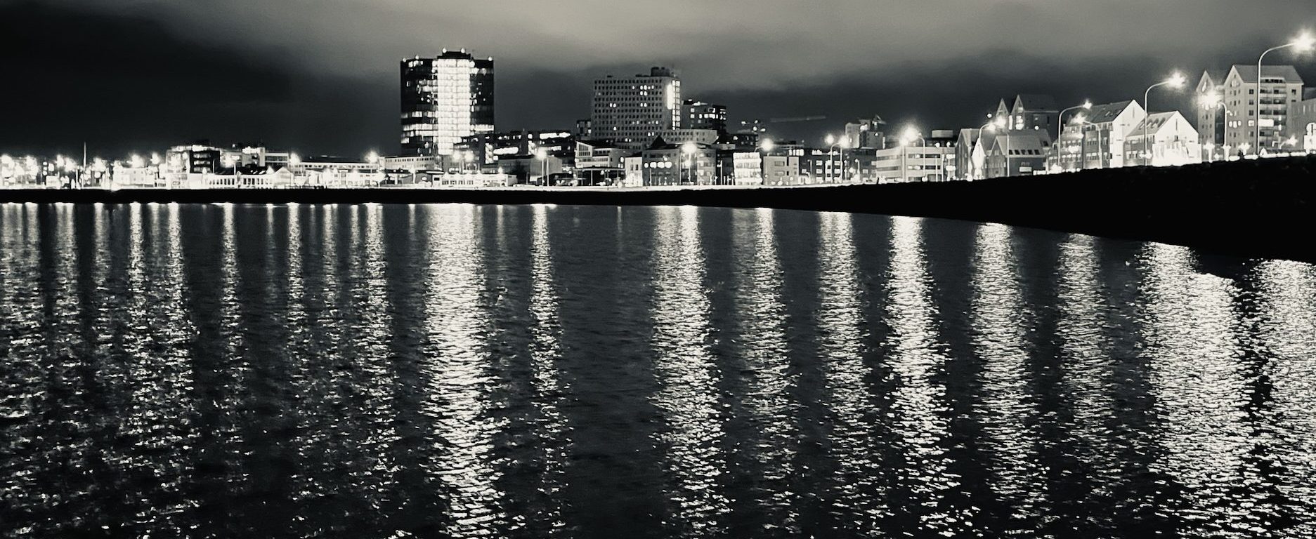A black and white shot of Reykjavik's coastline at night.