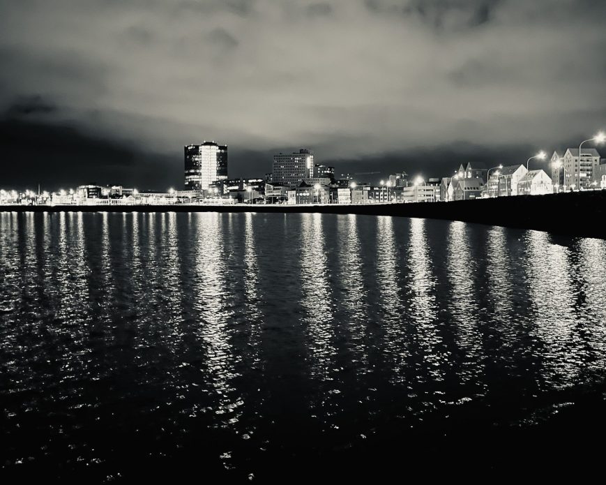 A black and white shot of Reykjavik's coastline at night.