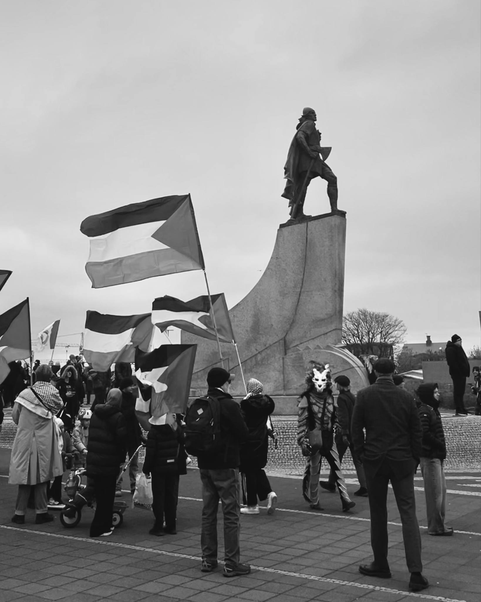 Pro-Palestine activists during the Labour Day March in Iceland. A masked figure looks directly into camera as he walks by.